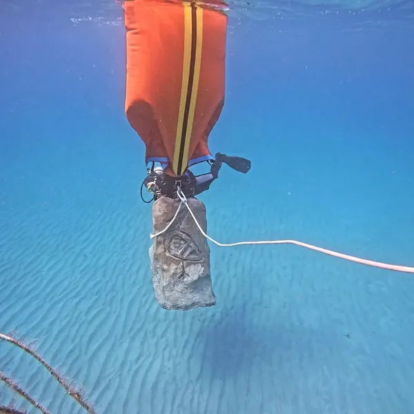 Orange lift bag raising a concrete mooring block from the seabed