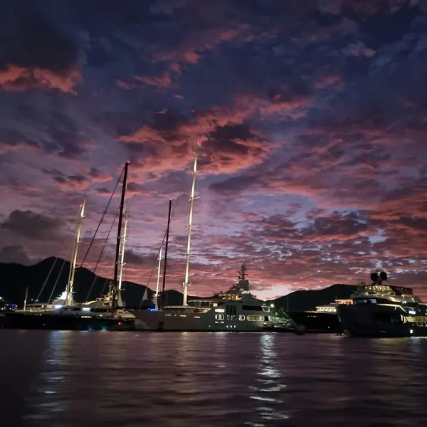 Sailing yachts and superyachts moored in a Sint Maarten harbour under a dramatic sunset sky